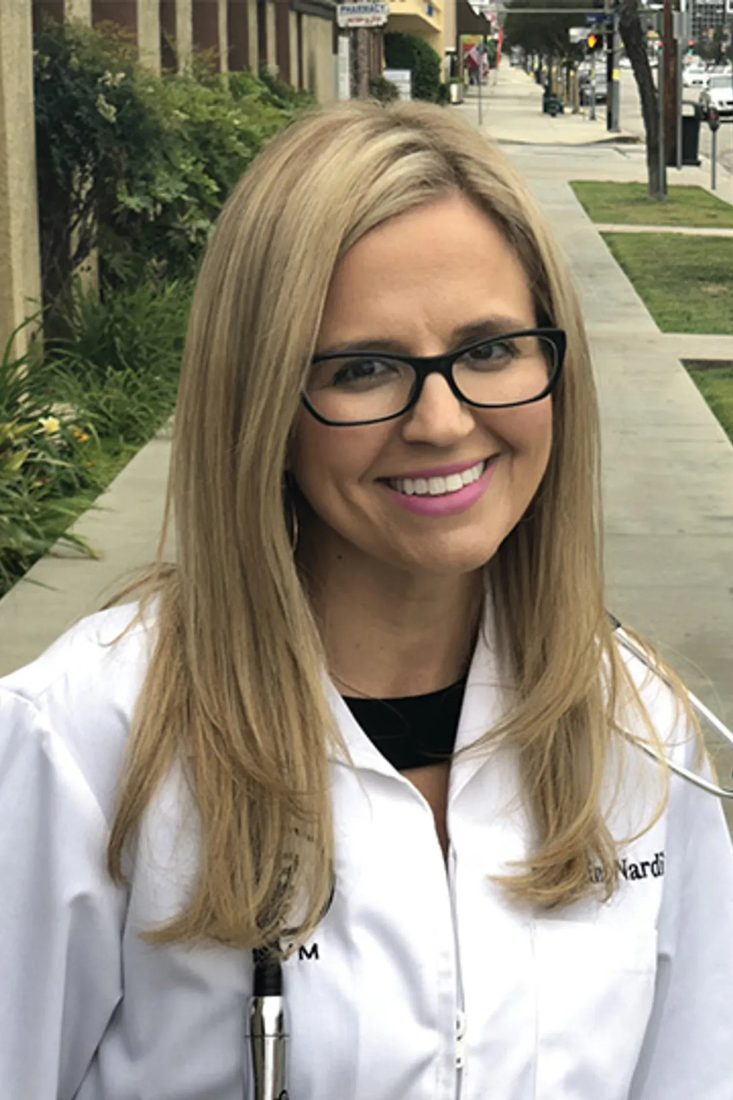 Smiling female veterinarian with glasses and stethoscope outdoors on a sidewalk